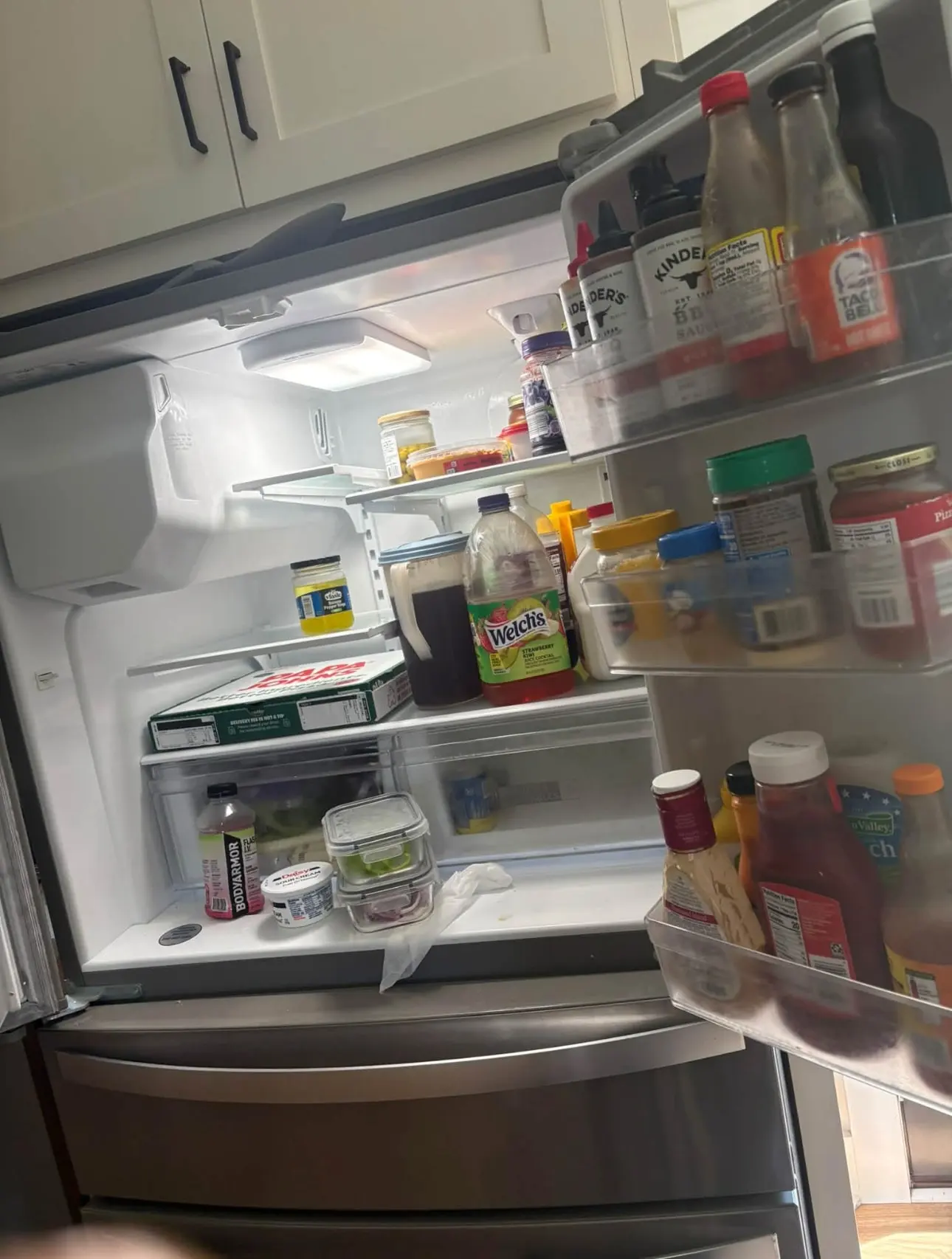 Before: crowded refrigerator with containers on the bottom shelf and a paper towel hanging out
