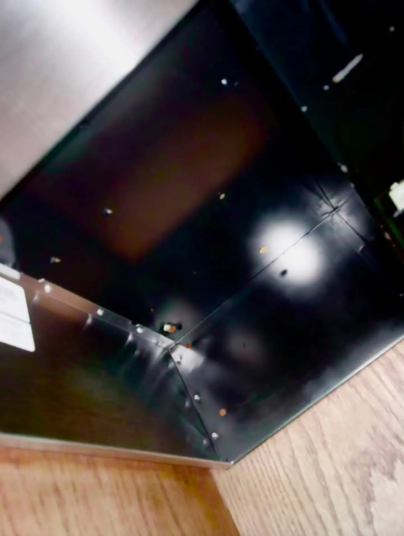 After: the same range hood underside, clean black metal