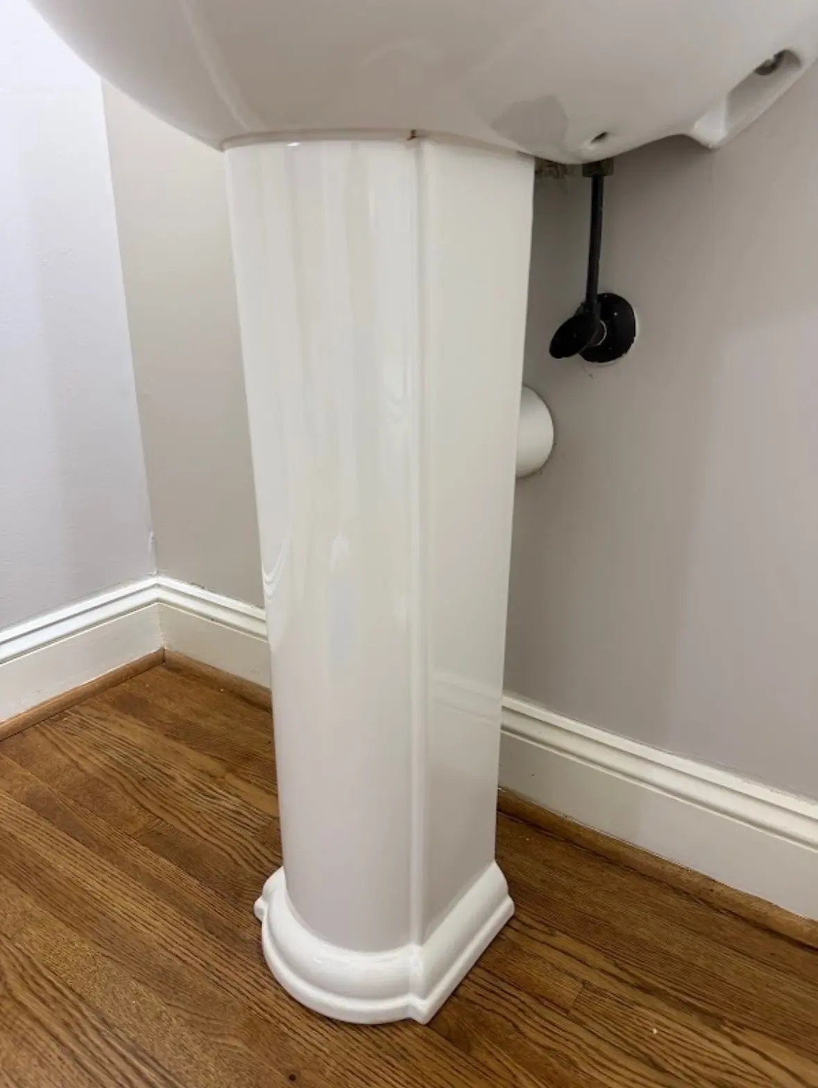After: the same pedestal sink and wall, clean and white
