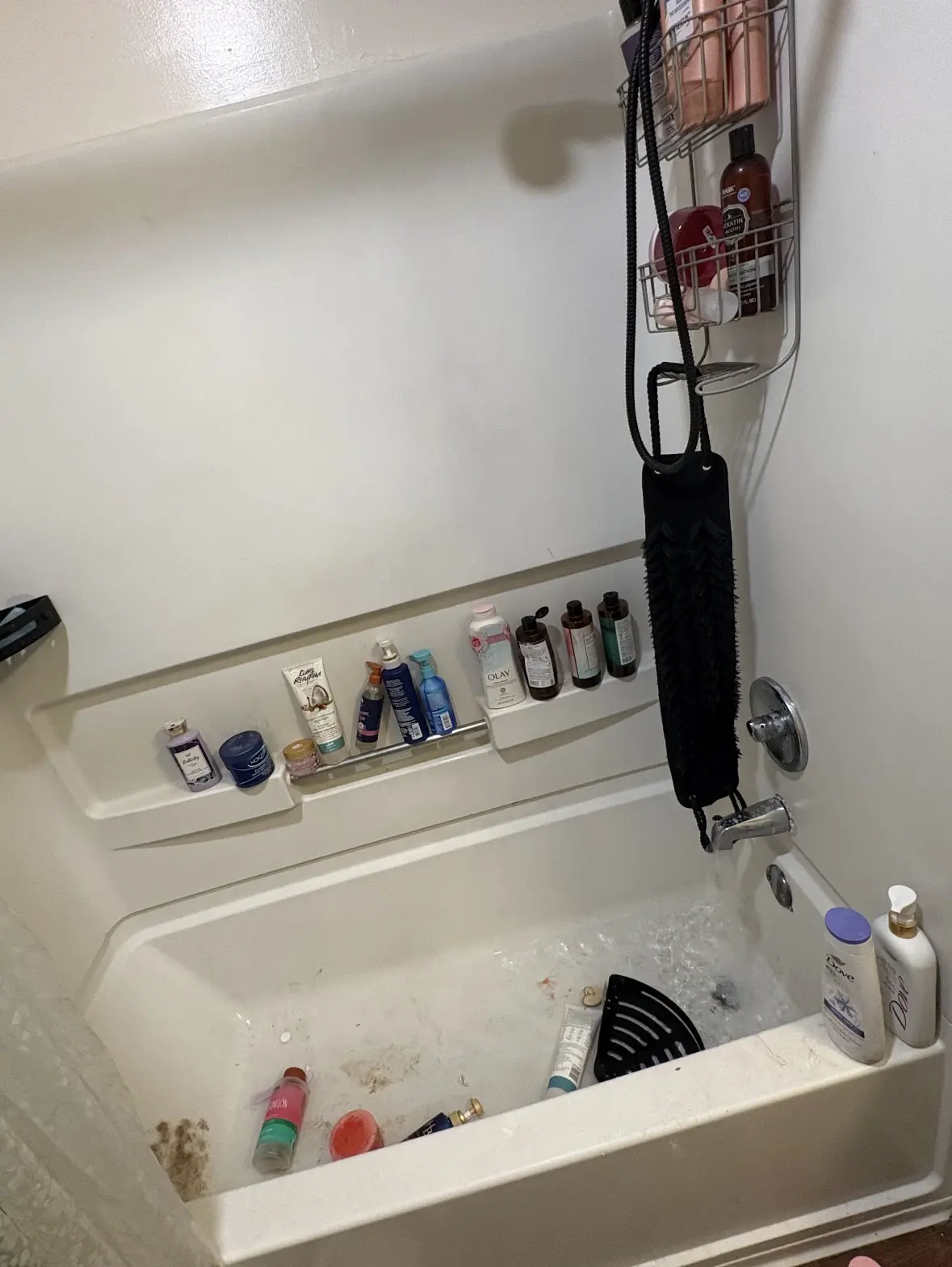 Before: bathtub floor with grime and hair, bottles scattered in the tub