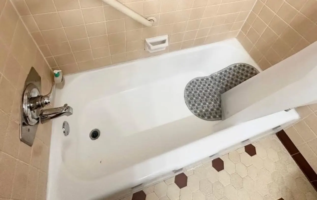 After: the same tub and tile rinsed clean, with a bath mat in place