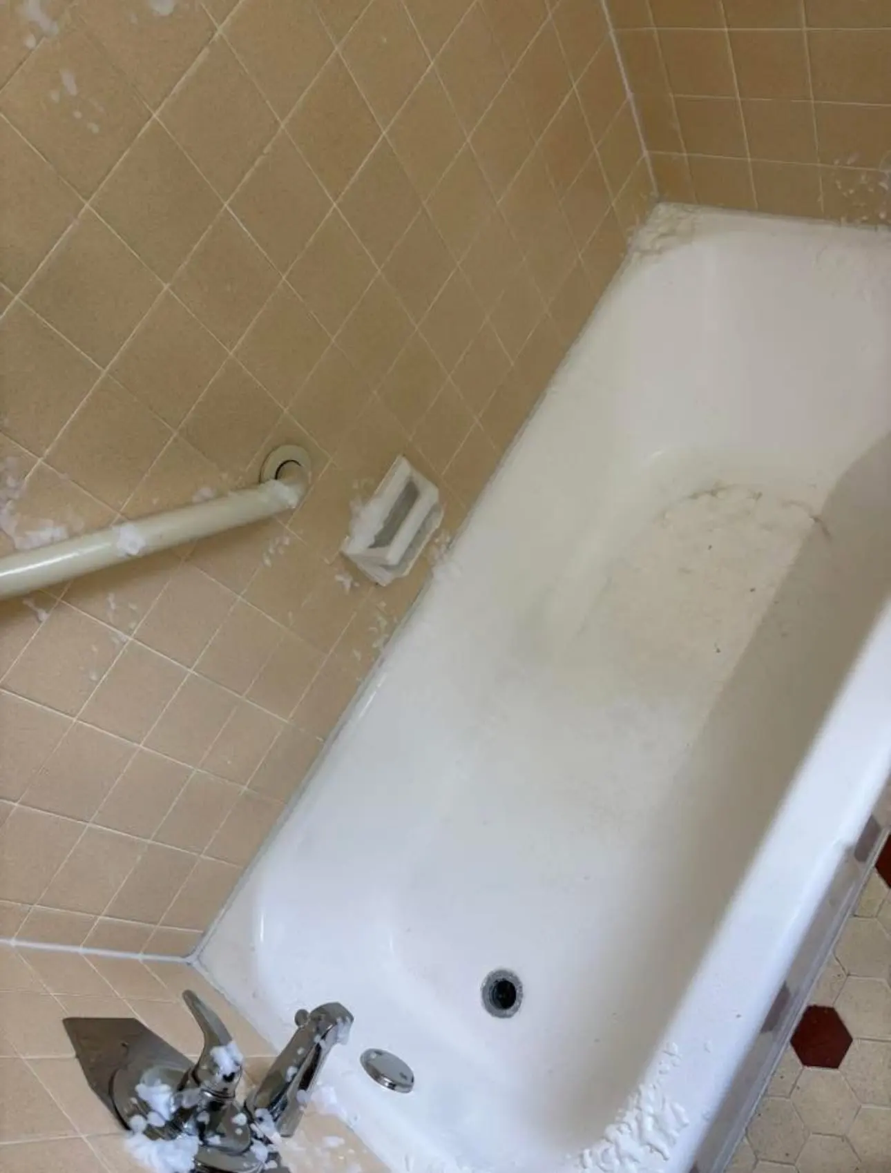During: cleaner foam working on the tile, grab bar, soap dish and faucet
