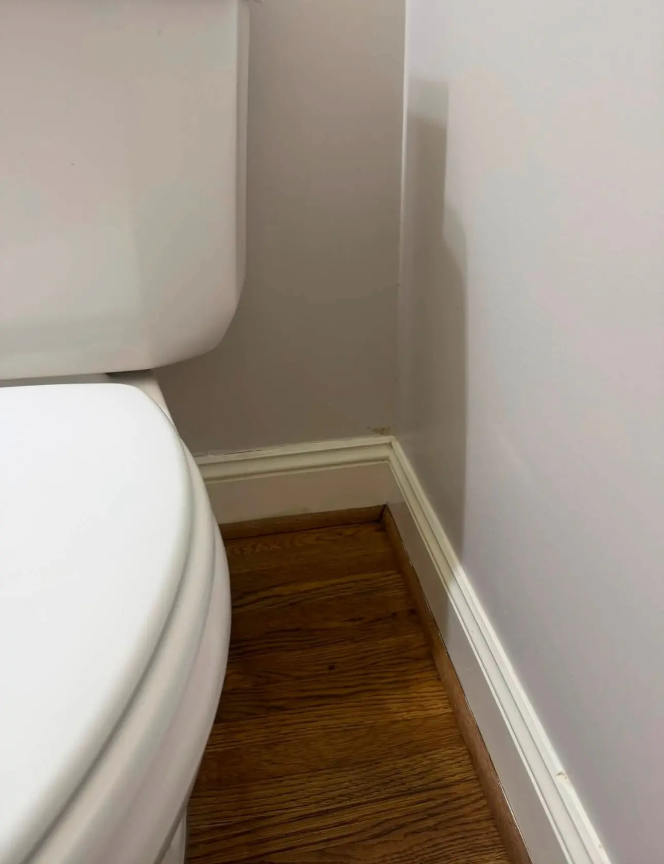 After: a clean wall and baseboard in another corner of the same bathroom